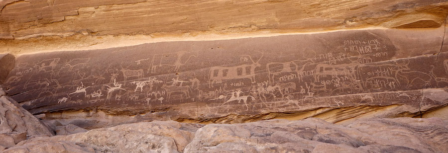 Graffiti in Himaitic Thamudic engraved on a long rock wall near Ḥimā, north of Najrān (Saudi Arabia). The wall shows numerous overlays. The texts, in particular, are more recent and superimposed on the hunting scenes with bovids. The knights, on the other hand, are noticeably more recent than both the texts and other rock drawings.